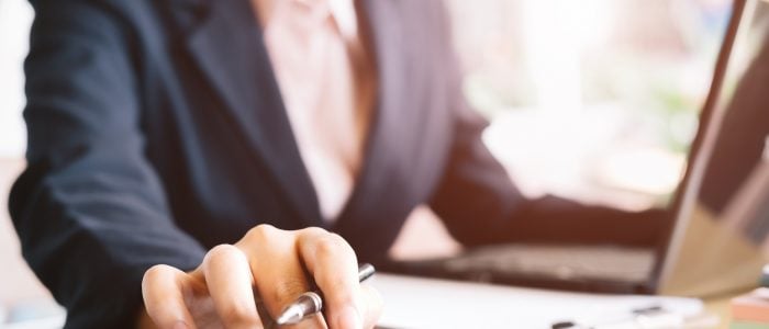 Stock photo of a businessperson sitting at their computer and doing calculations.