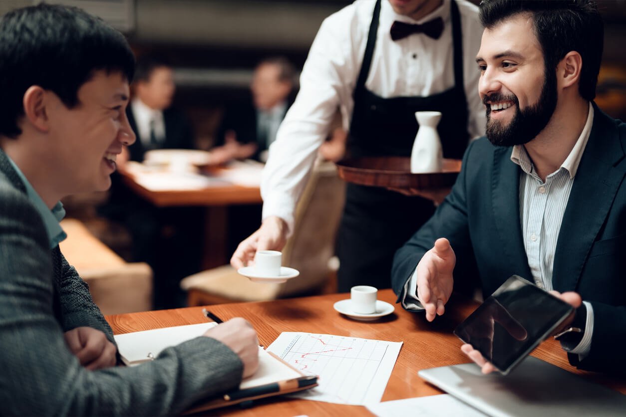 Stock image - Two business men at a restaurant dinner table being served drinks