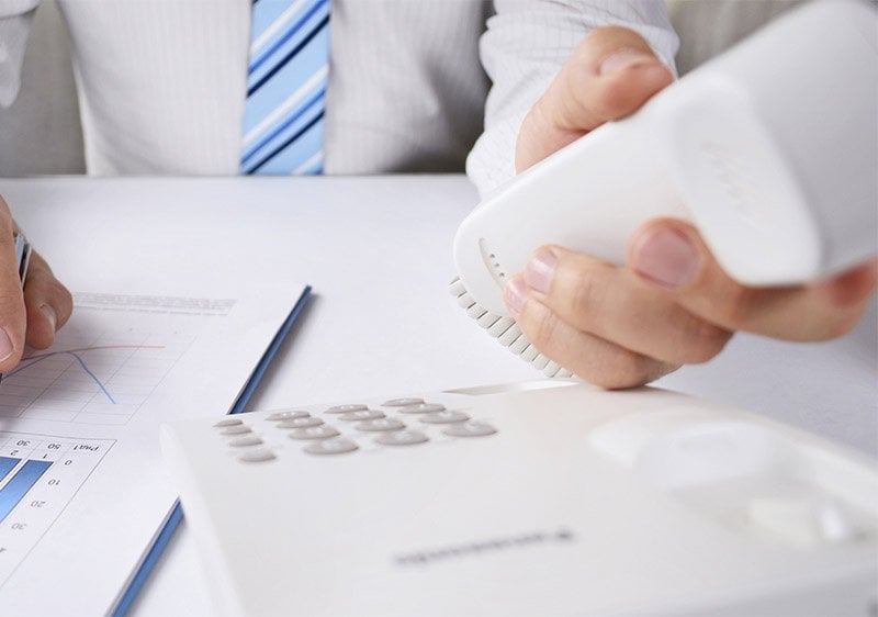 Stock image - a close up shot of an office worker picking up a telephone